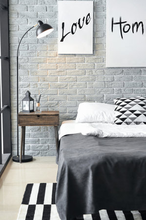Interior of stylish bedroom with posters, lamp and tableの写真素材