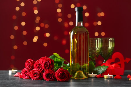 Bottle of wine, rose flowers and burning candles on black table against blurred lights. Valentine's Day celebrationの写真素材
