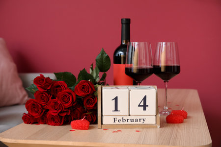 Calendar with date 14 FEBRUARY, wine and roses on table in living room, closeupの写真素材