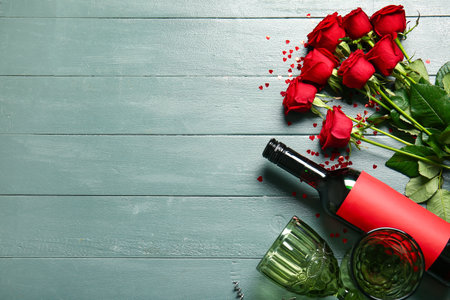 Bottle of wine, rose flowers and glass on green wooden background. Valentine's Day celebrationの写真素材