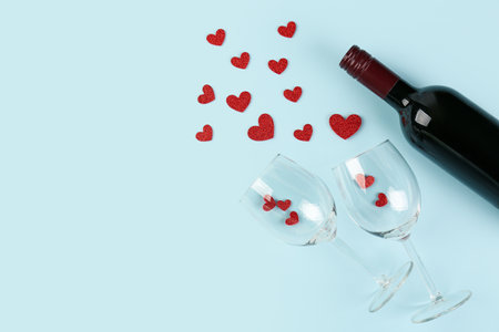 Bottle of wine, glasses and hearts on blue background. valentine's day celebrationの写真素材