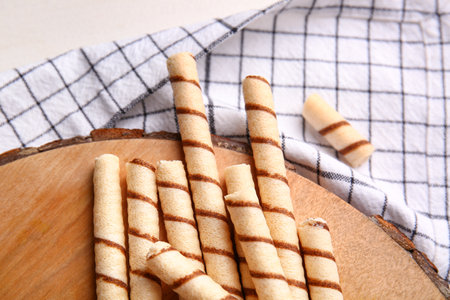 Cutting board with tasty wafer rolls and kitchen towel on tableの写真素材