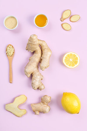 Fresh ginger roots, powder, lemon and bowl of honey on pink backgroundの写真素材