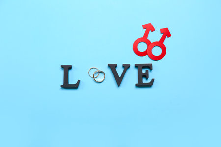 Word LOVE with wedding rings and man symbols on blue background. Valentine's Day celebrationの写真素材