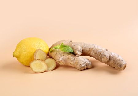 Fresh ginger, slices and lemon on beige backgroundの写真素材