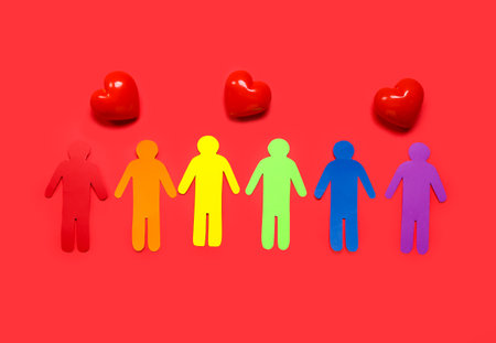 Hearts and paper human figures in colors of LGBT flag on red background. Valentine's Day celebrationの写真素材