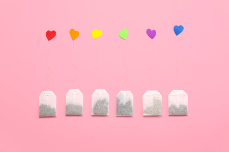 Tea bags and hearts in colors of LGBT flag on pink background. Valentine's Day celebration