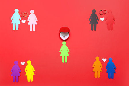 Paper female figures with hearts and wedding rings on red background. Valentine's Day celebrationの写真素材
