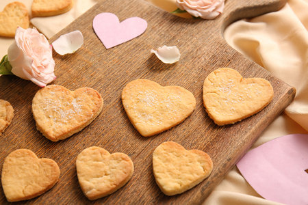 Wooden board with sweet heart shaped cookies and rose flower, closeup. valentine's day celebrationの写真素材