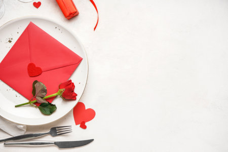 Table setting for Valentine's Day with envelope and rose on white tableの写真素材