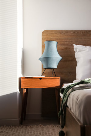 Wooden bedside table with lamp and magazine in the bedroom