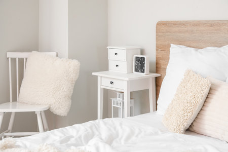 Bedside table with drawers and alarm clock in light bedroom