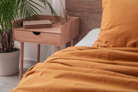 Wooden bedside table with books and reed diffuser in the bedroomの写真素材