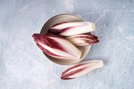 Bowl with bunches of fresh red endive on light backgroundの写真素材