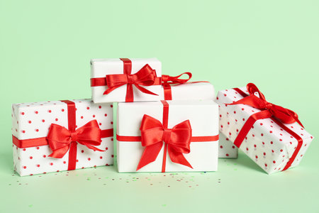 Gift boxes with beautiful bows on green background. Valentine's Day celebration