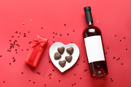 Bottle of wine, chocolate candies and gift box on red background. Valentine's Day celebrationの写真素材