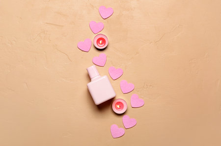 Perfume with burning candles and hearts for Valentine's day on beige backgroundの写真素材
