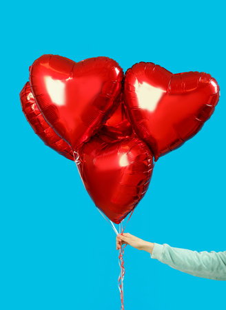 Woman with heart-shaped balloons for Valentine's Day on blue backgroundの写真素材