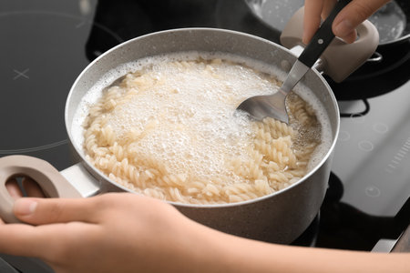 Woman cooking tasty pasta on stove, closeupの写真素材