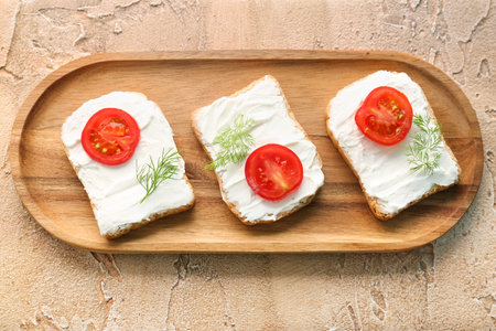 Wooden board of tasty bread rusks with cream cheese and tomatoes on color backgroundの写真素材
