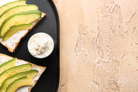 Plate of tasty sandwiches with cream cheese and avocado on color background, closeupの写真素材