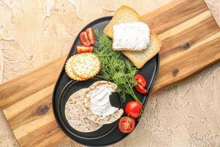 Plate of tasty crackers with cream cheese, dill and tomatoes on table