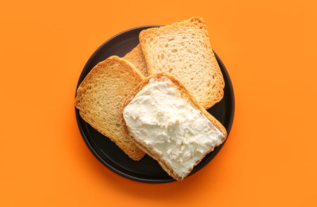 Plate of toasts with tasty cream cheese on color background