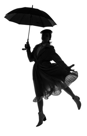Silhouette of stylish young woman with umbrella jumping on white backgroundの写真素材