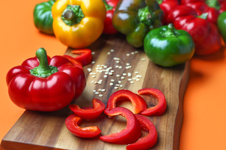 Wooden board of fresh bell peppers on color background, closeupの写真素材