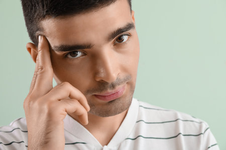 Thoughtful young man on green background, closeup