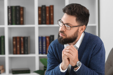 Thoughtful young bearded man in armchair at homeの写真素材