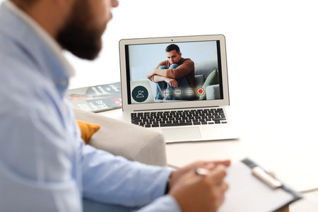 Male psychologist video chatting with patient at home, closeup