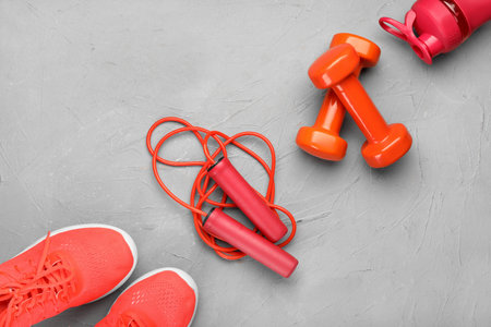 Skipping rope with sneakers, dumbbells and bottle on grunge backgroundの写真素材