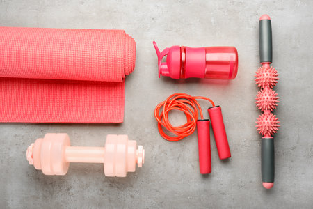 Skipping rope with massage roller, bottle, mat and dumbbell on grunge backgroundの写真素材