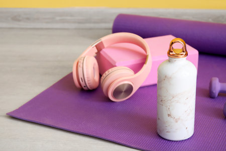 Sports water bottle with equipment and headphones on mat, closeupの写真素材