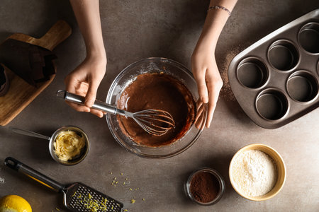 Woman preparing delicious chocolate muffins on dark backgroundの写真素材