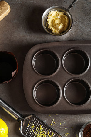 Muffin tray and butter on dark background, closeup
