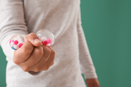 Young man with squeeze ball on green background, closeup
