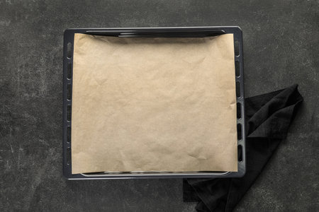 Baking tray with parchment paper and napkin on dark backgroundの写真素材