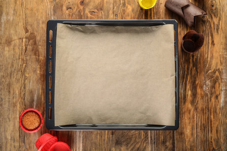Baking tray with parchment paper and muffin forms on wooden backgroundの写真素材