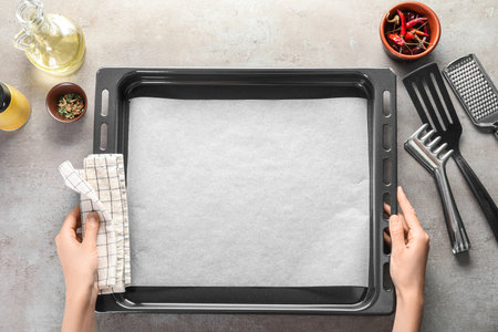 Woman with napkin, parchment paper, baking tray and ingredients on grunge backgroundの写真素材