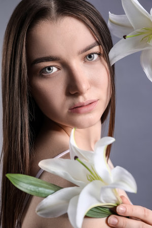 Young woman with white lilies on dark background, closeupの写真素材