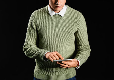 Young businessman using tablet computer on black background, closeupの写真素材