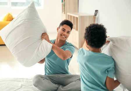 African-American boys fighting pillows in the bedroomの写真素材