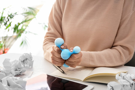 Woman squeezing stress ball while working in office