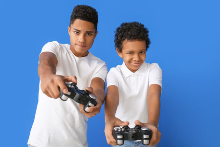 African-American boys playing video game on color background