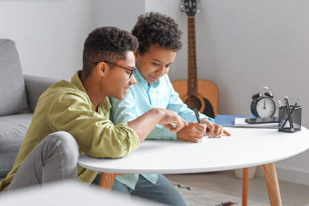 African-American boy helping his little brother to do lessons at homeの写真素材