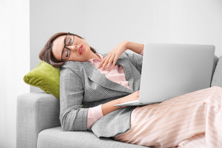 Young businesswoman falling asleep during work at homeの写真素材