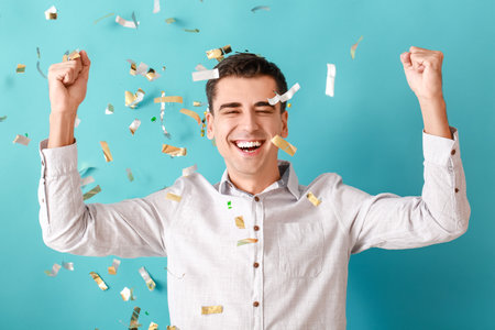 Happy man and falling confetti on color backgroundの写真素材