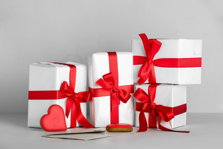 Gift boxes with beautiful bows and heart-shaped cookies on gray background. Valentine's Day...